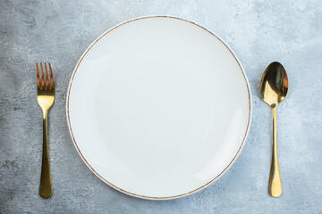 Elegant cutlery set and empty plate on gray background with distressed surface with free space