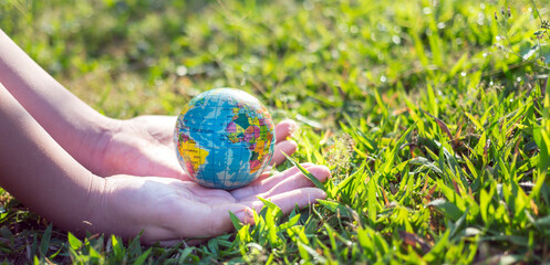 Earth Day or World Environment Day concept. Save our Planet and forest, Globe in hand on green grass