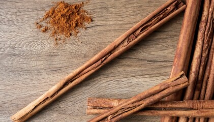 A top view of cinnamons sticks and powder with a wooden background