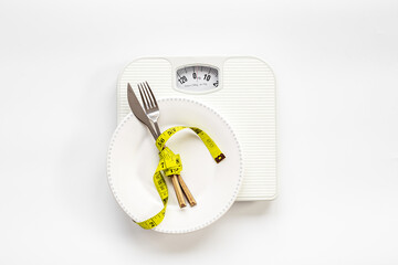 Tape measure with dinner cutlery and weight scales. Dieting and weight control concept