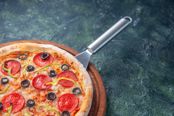 Half shot of delicious homemade pizza on wooden board on the right side on dark background