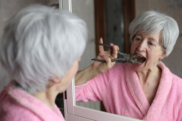 Senior woman self extracting a tooth with industrial pliers 