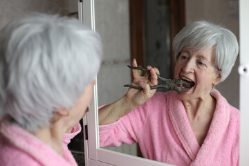 Senior woman self extracting a tooth with industrial pliers 