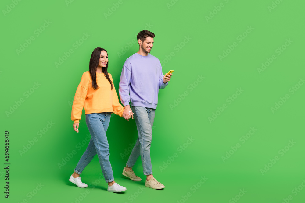 Poster Full size profile portrait of attractive lady handsome guy use telephone hold hands walk empty space isolated on green color background