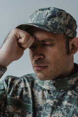 sad soldier in military uniform crying with closed eyes during memorial day isolated on grey.