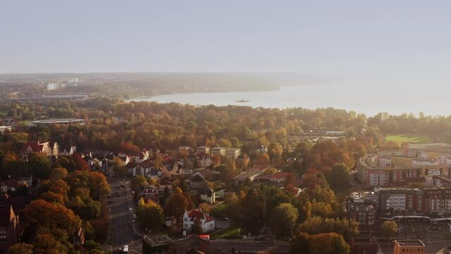 Drone flight backwards away from the famous "Tollensesee" with a view of a part of the city of Neubrandenburg with moving cars.