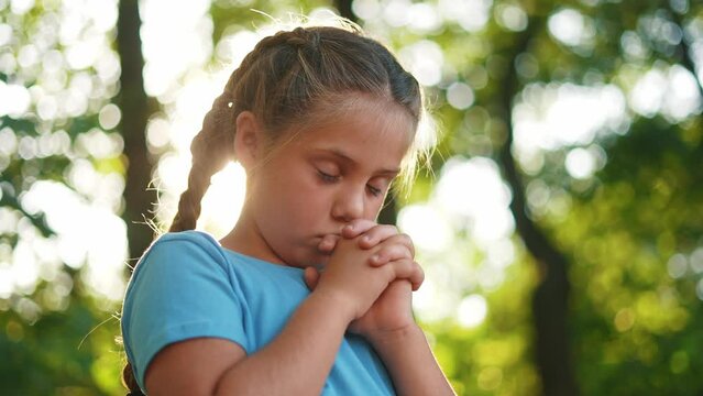 child pray. young gratitude a god religion concept. little girl in lifestyle nature outdoors praying dreams of happiness to god. praise worship freedom concept. kid praying in the forest
