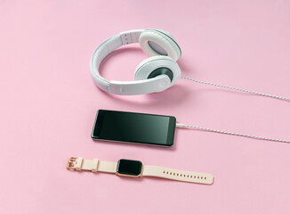Smart phone, smart watch and headphones on the pink surface. Healthy and active lifestyle