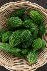 Close up Bitter melon bitter gourd cucumber or Momordica charantia in wooden bowl isolated on old wood table