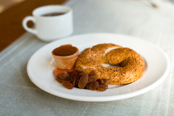 Turkish simit snack with sesame seeds on breakfast, jam and raisin topping