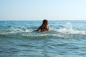 child splashing water, bathing at the sea on vacations, having fun