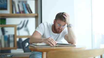 Portrait of tired overworked guy, exhausted young man in glasses college or university student is study hard in library, prepare to exam, lesson