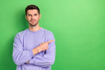 Photo of charming pretty young man wear purple smiling showing finger empty space isolated green color background