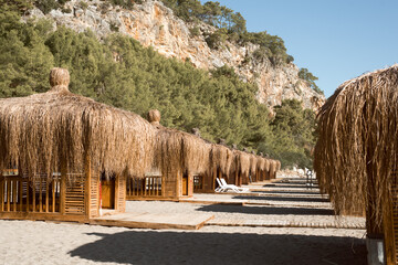 Wooden beach pavilions on the shore with mountains - the Mediterranean coast