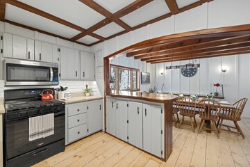 a kitchen with wood floors and ceiling beams next to an oven