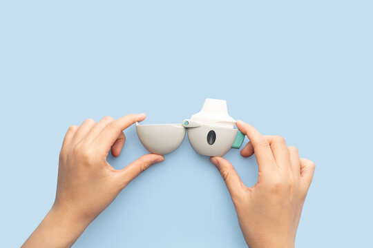 Asthma and COPD concept. Female hand holding Tiotropium bromide  inhaler on blue background. Pharmaceutical device of bronchodilator for lung inflammation treatment and prevent asthma attack.