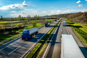 Heavy Highway transportation scene with Convoy of white transportation trucks in one way and blue...