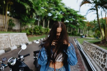 Naklejka na ściany i meble Portrait of a woman brunette smile with teeth walking outside against a backdrop of palm trees in the tropics, summer vacations and outdoor recreation, the carefree lifestyle of a freelance student.