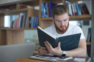 Portrait of serious concentrated guy, young man in glasses college or university student is study hard in library, prepare to exam, lesson