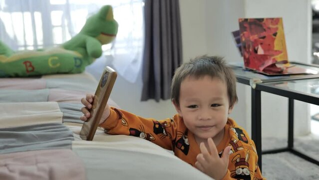 Little boy playing and watching smartphone on living room shofa