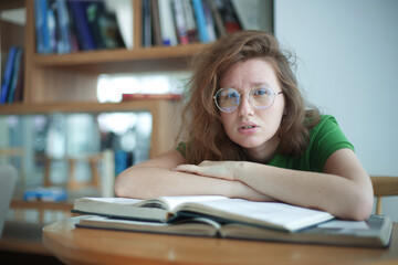 Portrait of serious concentrated, young woman in glasses college or university student is study hard in library, prepare to exam, lesson