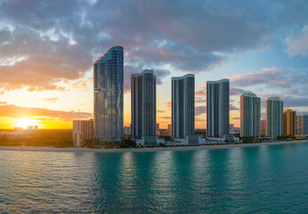 Evening landscape of sandy beachfront in Sunny Isles Beach city with luxurious highrise hotels and condo buildings on Atlantic ocean shore. American tourism infrastructure in southern Florida