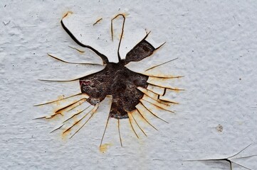 Texture of a white wall with a rust-covered hole