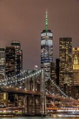 Fototapeta na wymiar Brooklyn Bridge illuminated with lights at night on the background of the modern cityscape