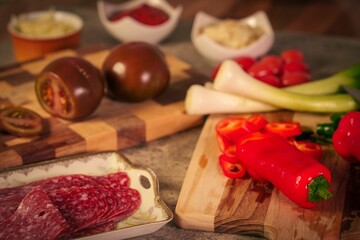 Variety of food items including meats and other ingredients on cutting boards before making pizza