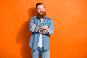 Photo of confident red hair businessman wear denim trendy look crossed hands look empty space popular influencer isolated on orange color background