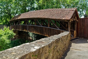 Wooden bridge in Rothenburg ob der Tauber spans a river and is supported by two stone pillars