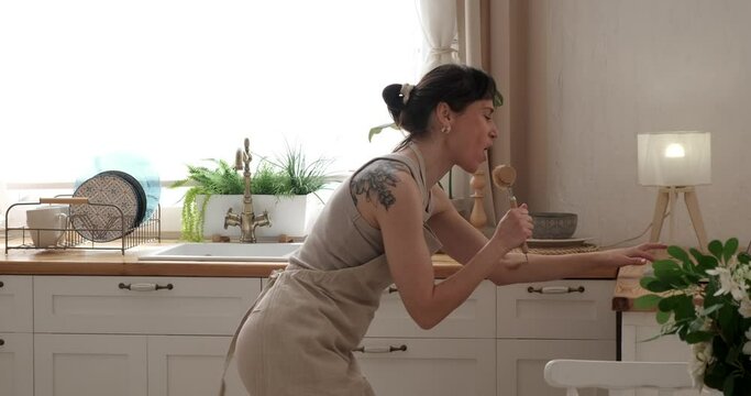 Woman dancing in kitchen at home having fun listening and singing her favourite music
