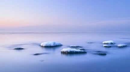Obraz premium Tranquil winter scene with a picturesque skyline reflecting off of the snow-covered rocks below