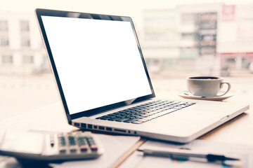 laptop is placed on a desk with a pen and coffee calculator.