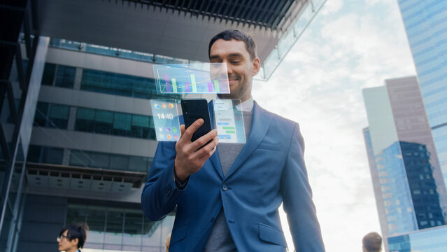 On Busy City Street Handsome Businessman Uses Smartphone with Edited Visual Holographic Screens Show Business Graphs, Charts and Stock and Crypto Market Analysis Statistics. Mock-up Mobile OS UI/UX.