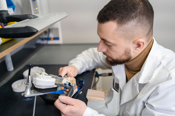 man working with articulator in dental lab. Dental technician manufacturing orthodontic prosthesis. Workplace of a dental technician