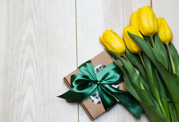 Gift box and tulips on light background