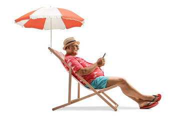 Mature man sitting on a beach chair under umbrella with a smartphone