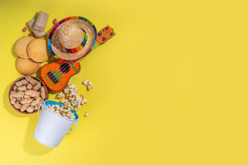 Brazilian Festa Junina Summer Festival, holiday greeting card, invitation Background. Brazilian straw hat, popcorn, peanuts, guitar, corn cookies, with colorful flags on yellow background