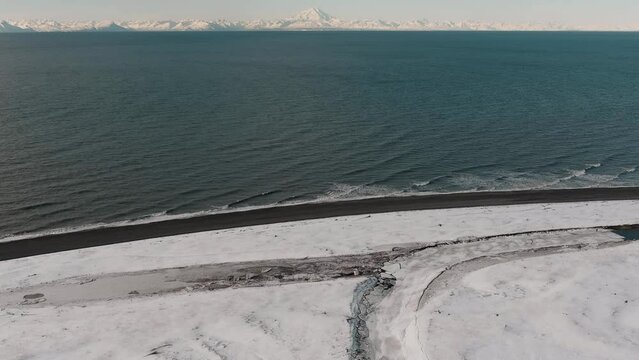 View of Mount Redoubt, Alaska in the winter with the Cook Inlet Ocean in the foreground - panning up