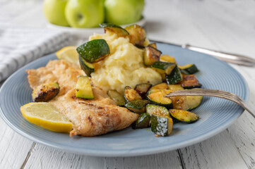 Pan fried fish fillet with mashed potatoes and roasted zucchini on a plate