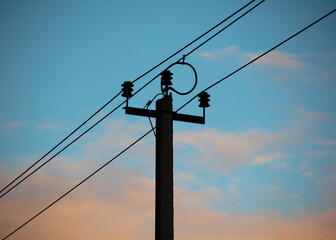Electric pole with wires on the background of the sunset