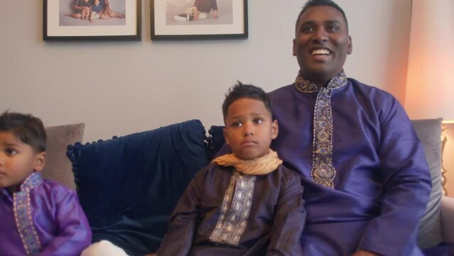MS Father and sons (2-3, 6-7) sitting on sofa in traditional clothing