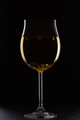 Glass of white wine on black background