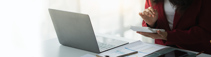 copy space, panorama, banner business woman using calculator to calculate financial figures Income tax in the real estate business by analyzing data Detail on laptop computer inside office.