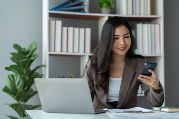 Smiling beautiful young Asian businesswoman ready to press the phone Talking on the mobile phone in the office with a happy smile.