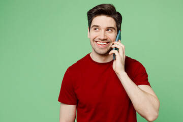 Young happy man he wears red t-shirt casual clothes talk speak on mobile cell phone conducting...
