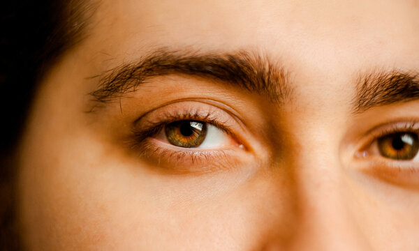 A close-up of a man's face, with his piercing brown eyes taking center stage.  This image evokes a sense of mystery, leaving the viewer wondering about the thoughts behind those piercing eyes. 