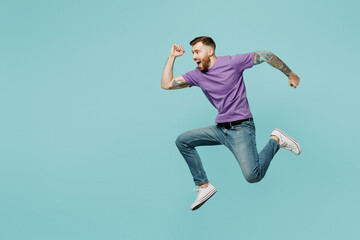 Full body stylish sporty strong winner fun young man he wears purple t-shirt jump high run fast hurry up in rush isolated on plain pastel light blue cyan background studio portrait. Lifestyle concept.