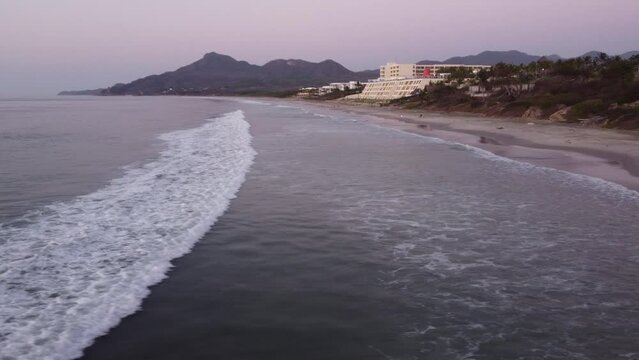 Aerial of the foamy waves of the ocean hitting the sandy beach in Punta Mita, Puerto Vallarta Mexico